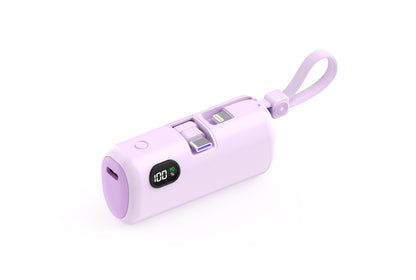 The picture shows a purple portable power bank with a digital display showing 100% power, featuring a wrist strap and multiple charging ports.
