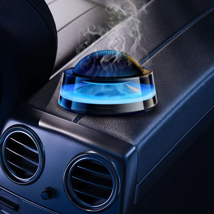 The picture shows a sleek, blue - lit car air freshener placed on the dashboard, emitting a soft light and presumably dispensing fragrance.
