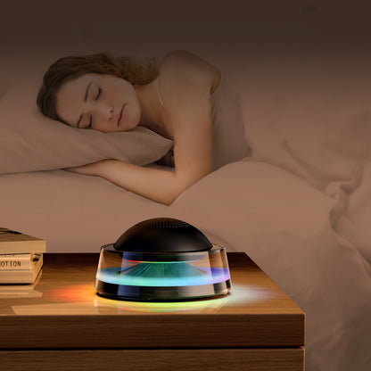 The picture shows a woman sleeping peacefully in bed, with a bedside device that appears to be an air purifier or aroma diffuser emitting colorful lights.
